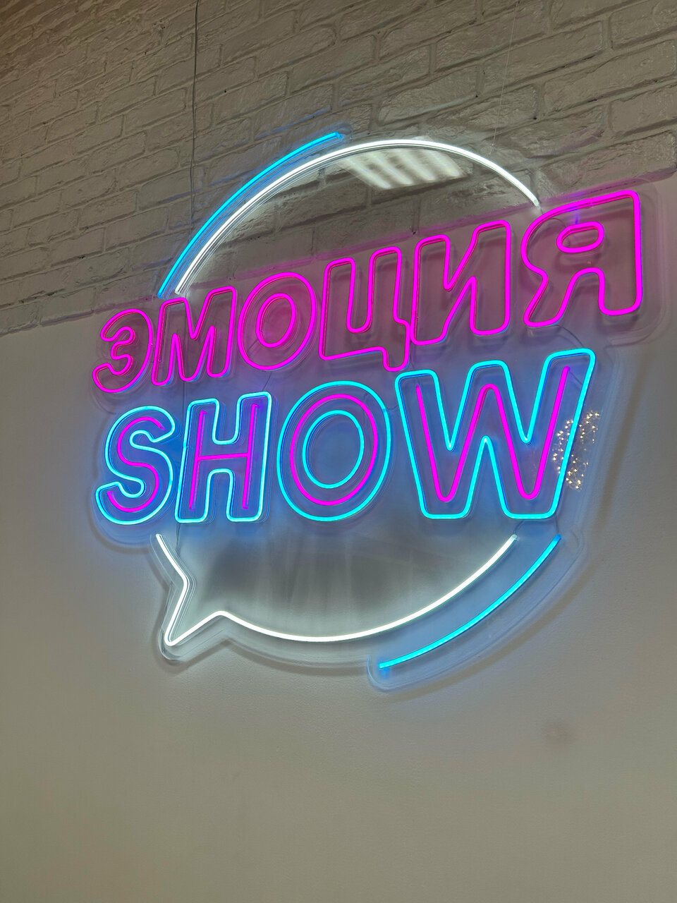 Неоновая вывеска «Эмоция Show» на кирпичной стене